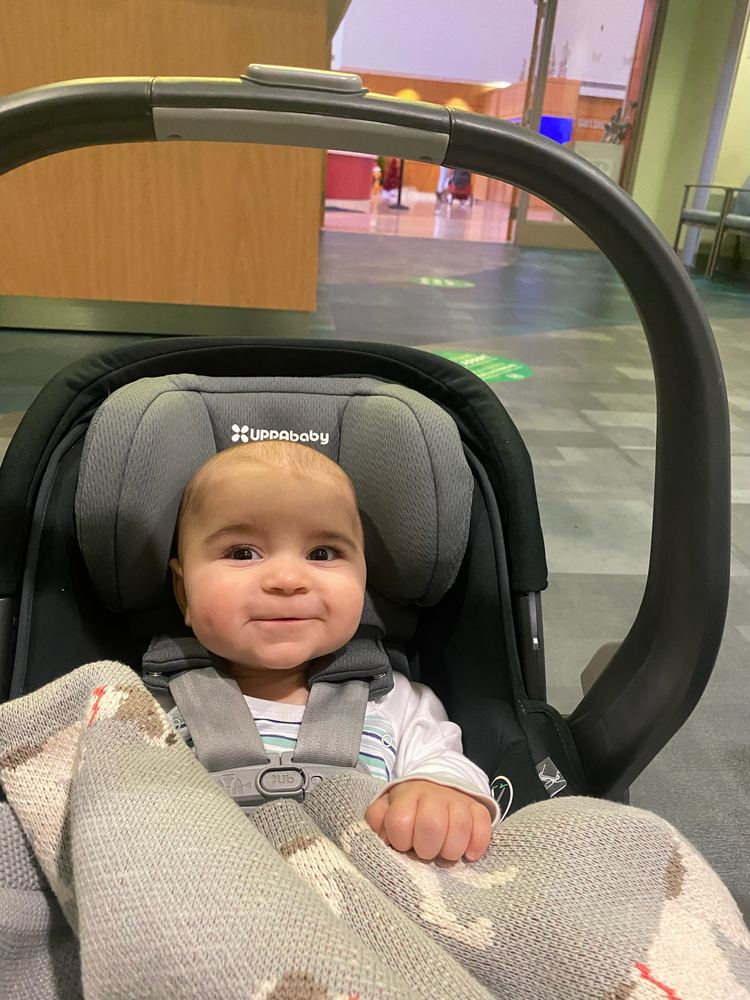 Benji as a baby, smiling in his car seat at the hospital