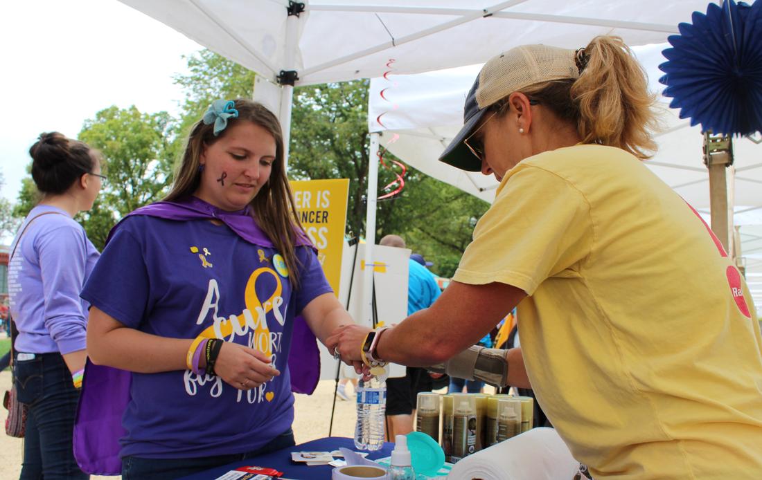 A Rally volunteer tying an awareness bracelet on a supporter at an event