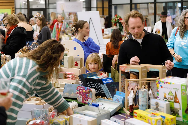 Shoppers browsing vendor tables at the Holiday Shopping Soirée