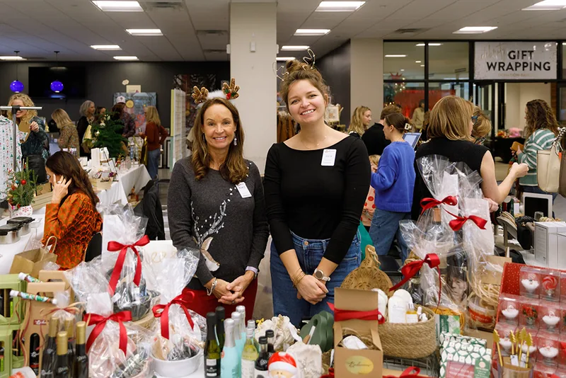Volunteers beside gift baskets at the Holiday Shopping Soirée