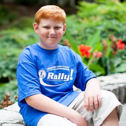 Rally Kid Drew sitting outdoors in a blue Rally t-shirt